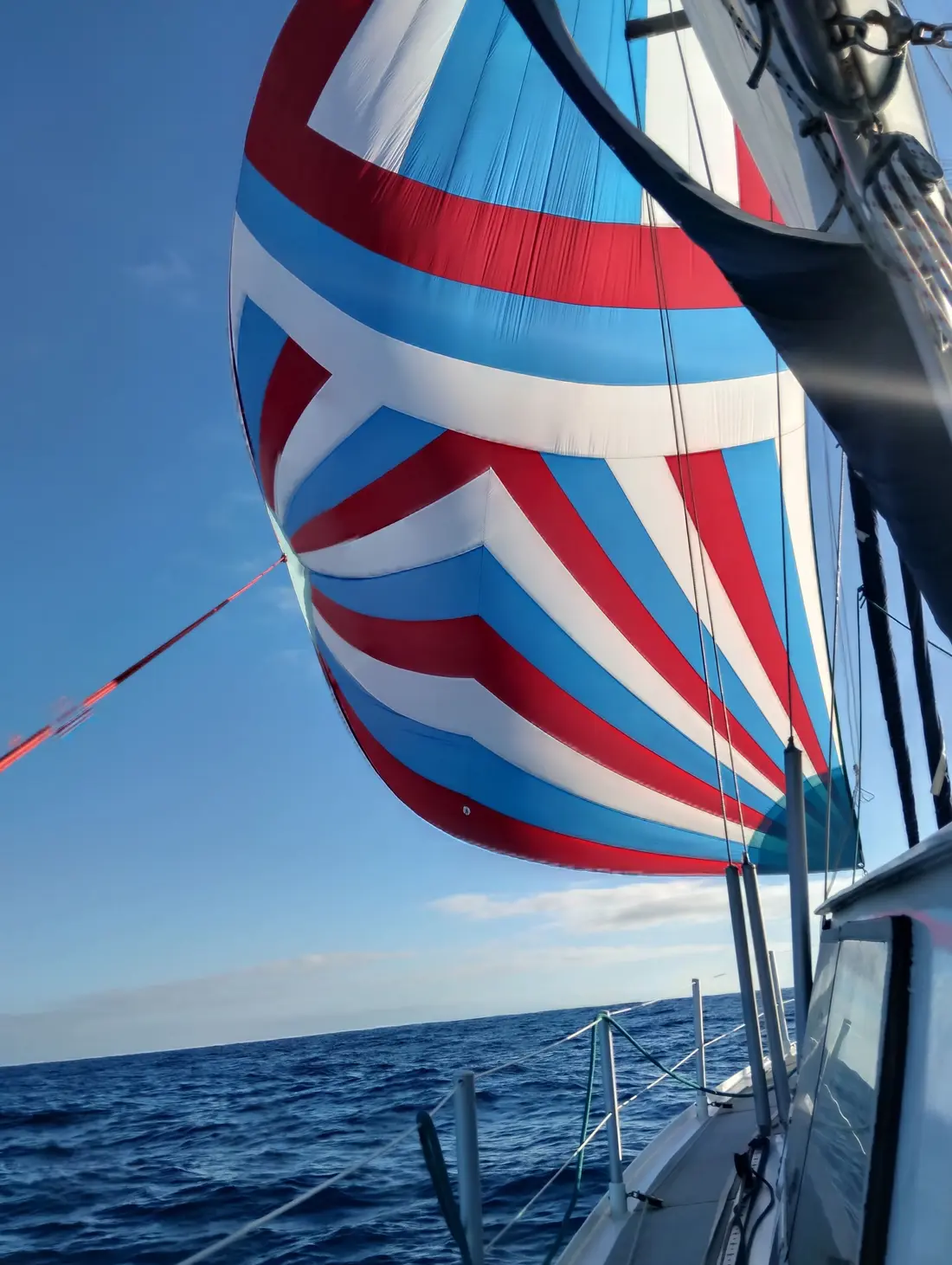 Spinnaker bleu, blanc et rouge gonflé au-dessus de l'océan